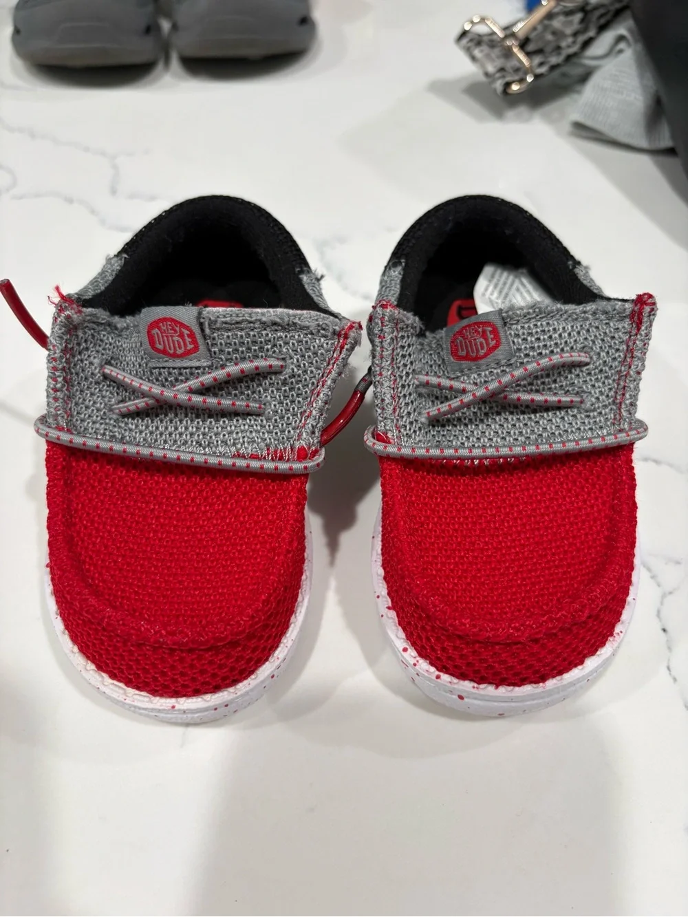 Hey Dude Kids Red and Gray Slip-On shoes.